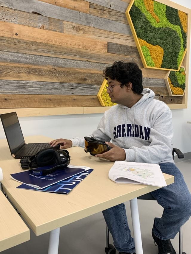 Interaction Design student Andrew George Geevarghese sits at a table working on a laptop computer