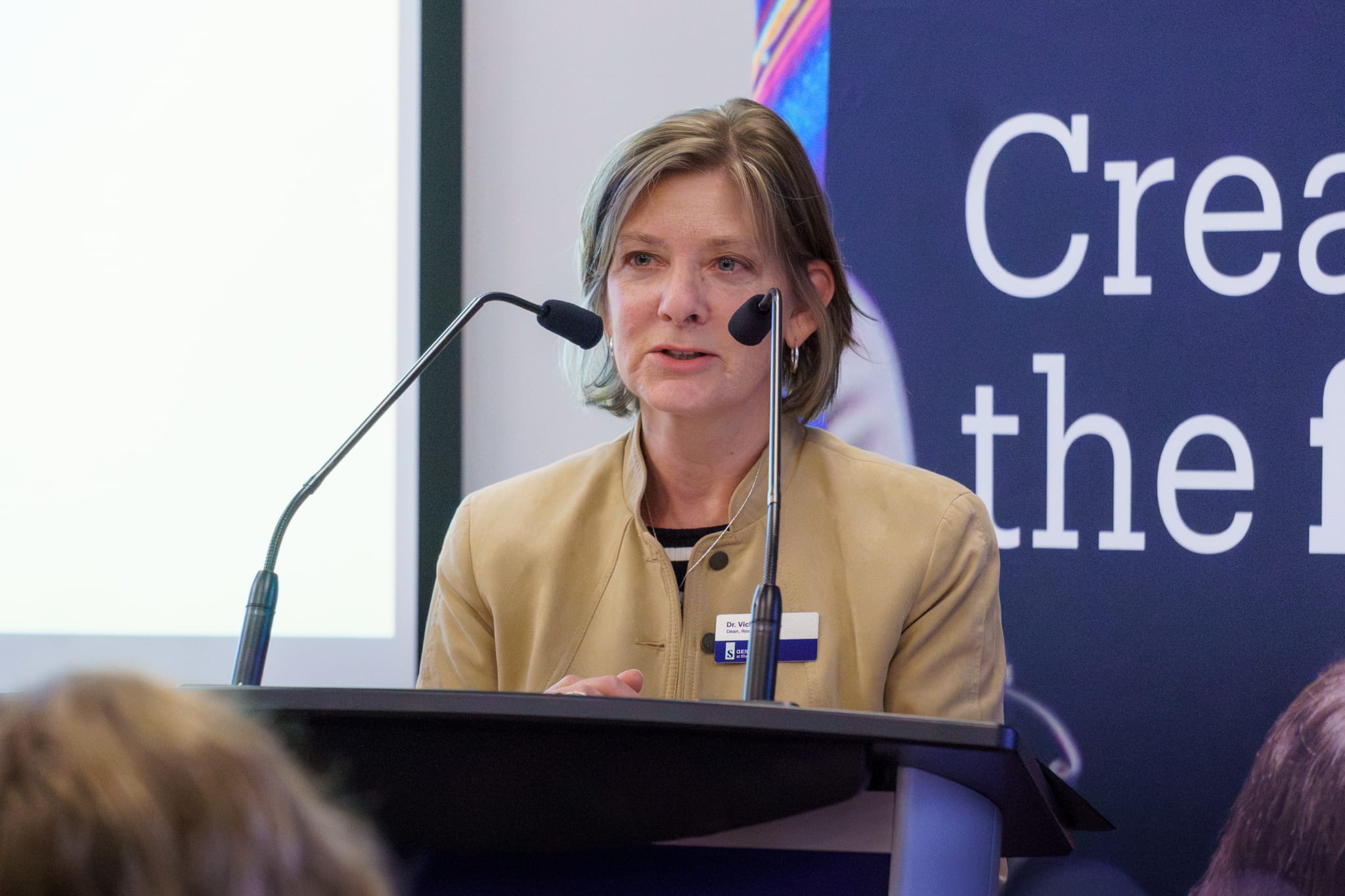 Sheridan Dean of Research Dr. Vicki Mowat stands at a podium delivering welcoming remarks