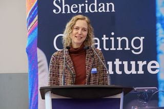 Generator at Sheridan Director of Research and Innovation Dr. Carolyn Moorlag stands behind a podium delivering remarks