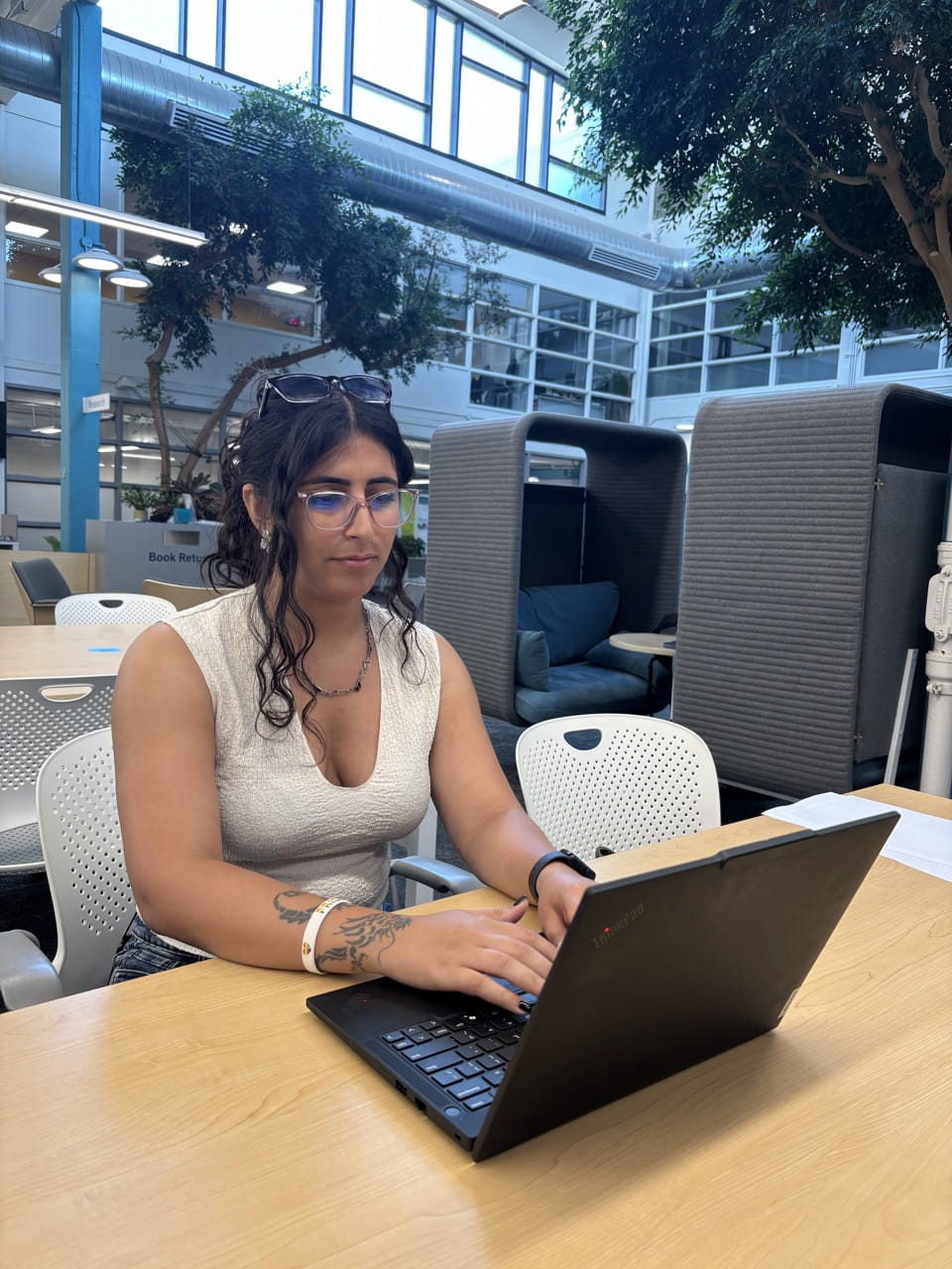 A student is pictured seated at a table working on a laptop