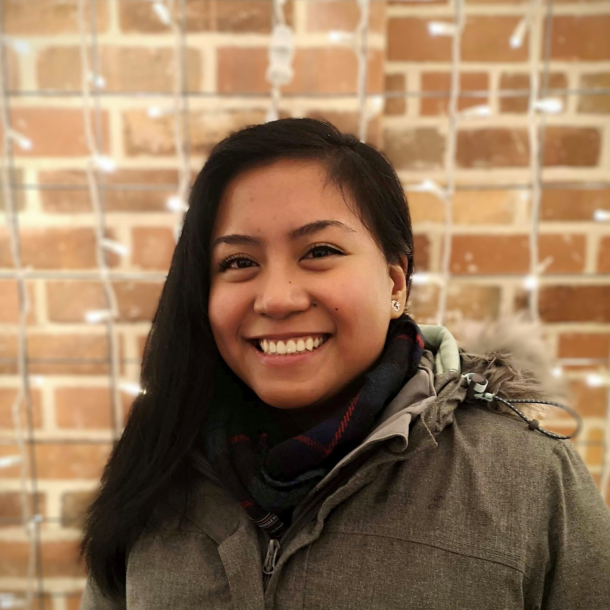 A head and shoulders photo of Bachelor of Computer Science student Jerikka Sotelo standing in front of a brick wall
