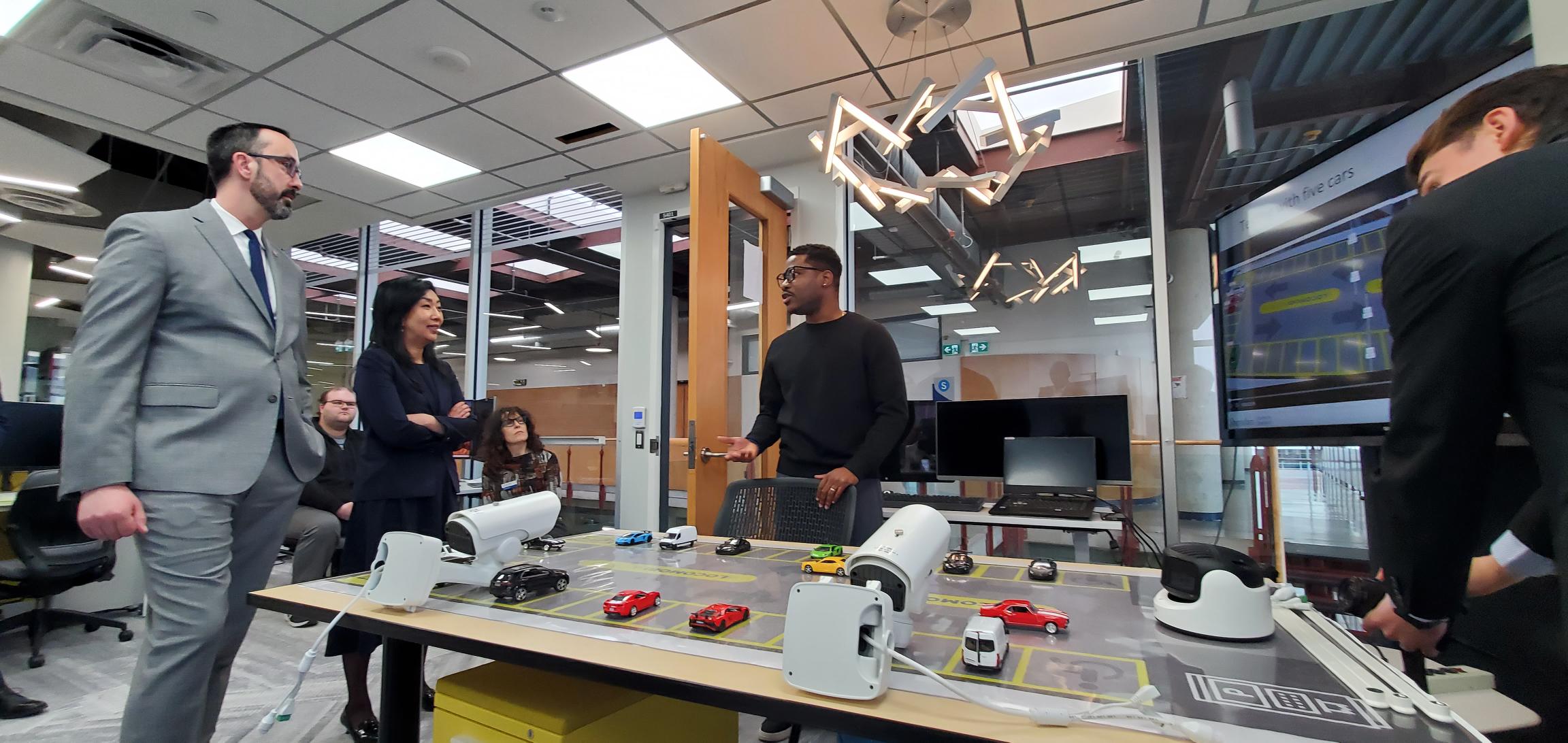 Nolan Quinn, Ontario Minister of Colleges, Universities, Research Excellence and Security, and Sheridan President Dr. Cindy Gouveia converse with a student inside Sheridan's Centre for Applied AI