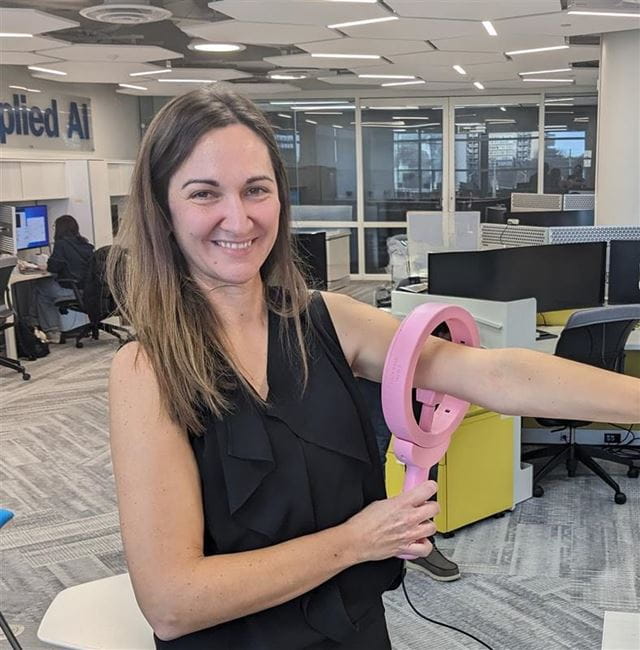 A researcher displays a StrongArms-Cancer device positioned around their elbow