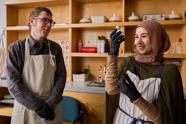 Experiential Design student Samira Elbehairy smiles as she looks at the contents of a glass jar while a Sheridan researcher looks on