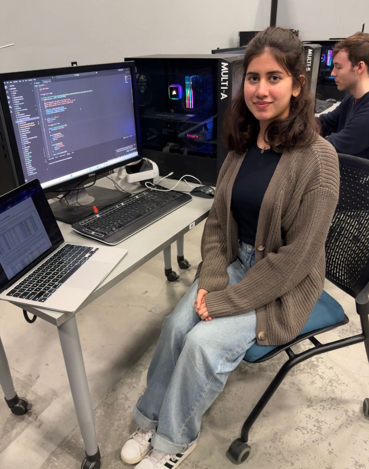 Sheridan student researcher Shehnazdeep Kaur is pictured sitting at a computer desk at Sheridan's Screen Industries Research and Training Centre (SIRT)
