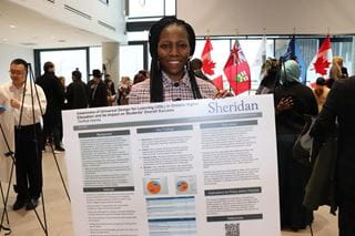 Sheridan student Taofikat Atanda holds a poster that summarizes her research project and key findings