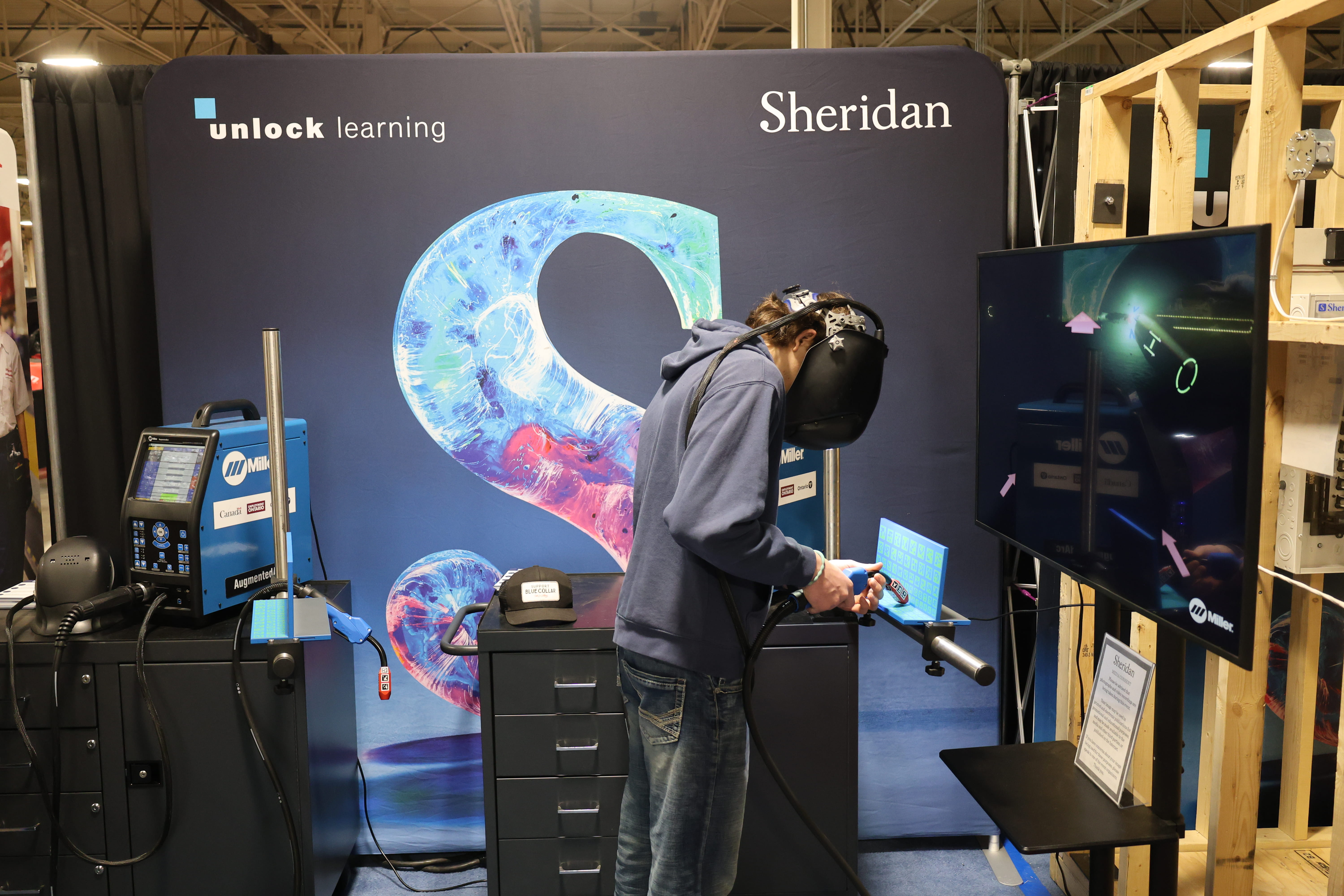 A person interacts with the virtual welding simulator at Sheridan's booth