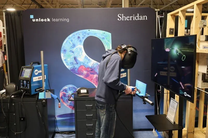 A person interacts with the virtual welding simulator at Sheridan's booth