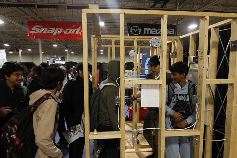 Visitors to Sheridan's booth interact with an electrical wiring simulation