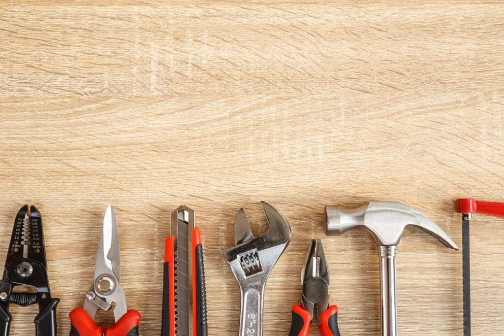 A photo of different tools against a wooden backdrop