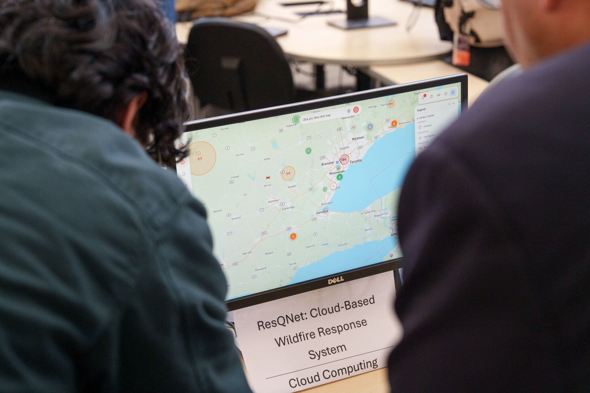 Two people look at a computer screen displaying a cloud-based wildfire response system