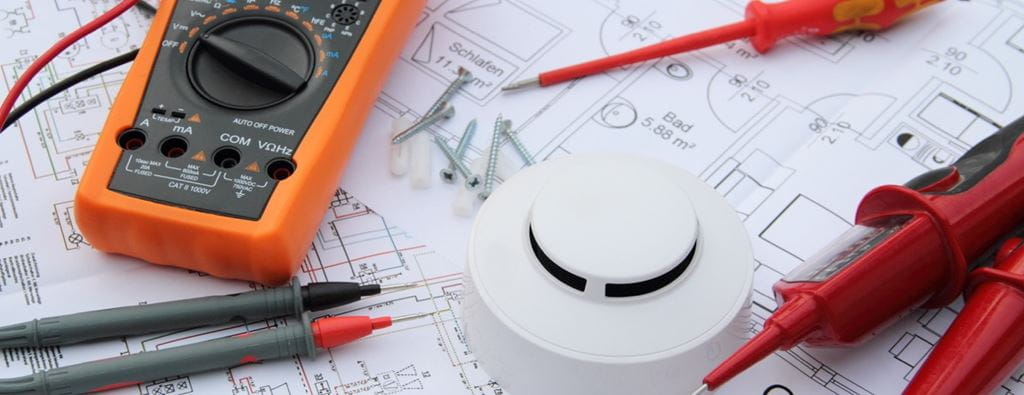 Electrician tools are pictured sitting on top of a wiring diagrams