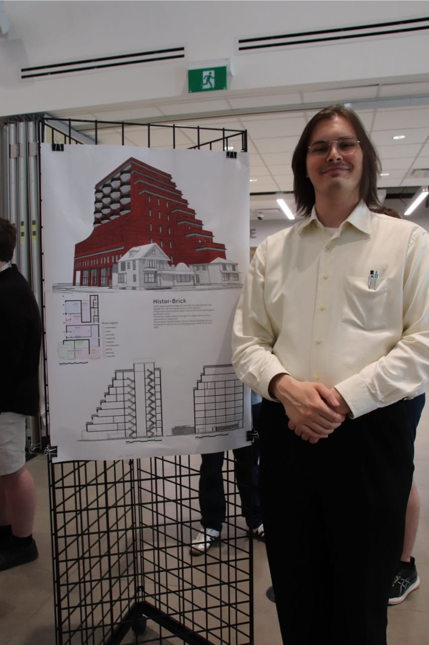 Sheridan student Cal Juedy stands beside a display of his project
