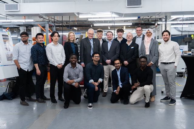 Sheridan mechanical engineering students stand with administrators, faculty and the capstone showcase judge for a photo within Sheridan's Centre for Intelligent Manufacturing.