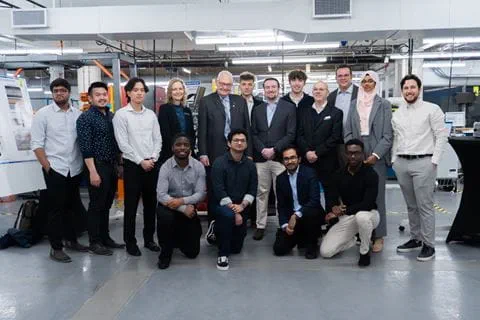 Sheridan mechanical engineering students stand with administrators, faculty and the capstone showcase judge for a photo within Sheridan's Centre for Intelligent Manufacturing.