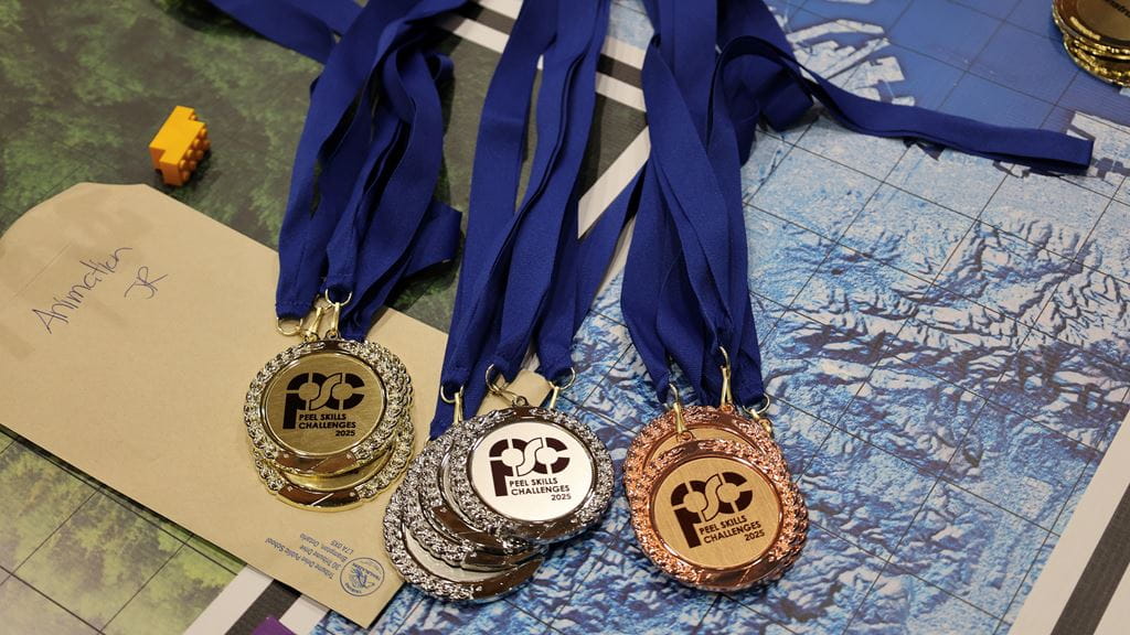 Gold, silver and bronze medals on a blue ribbon on a table. 