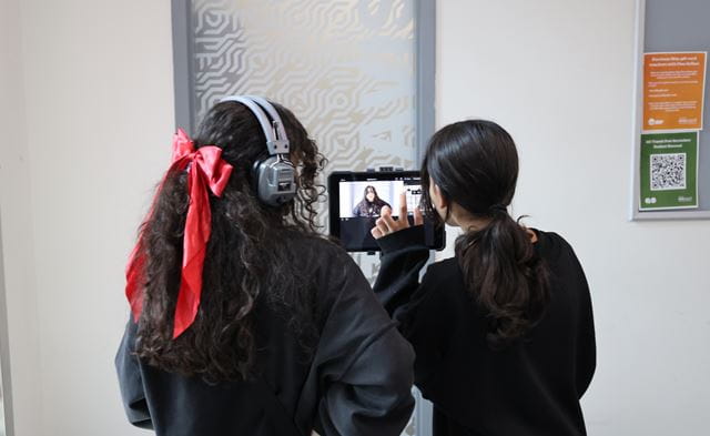 Two students face a camera screen. 