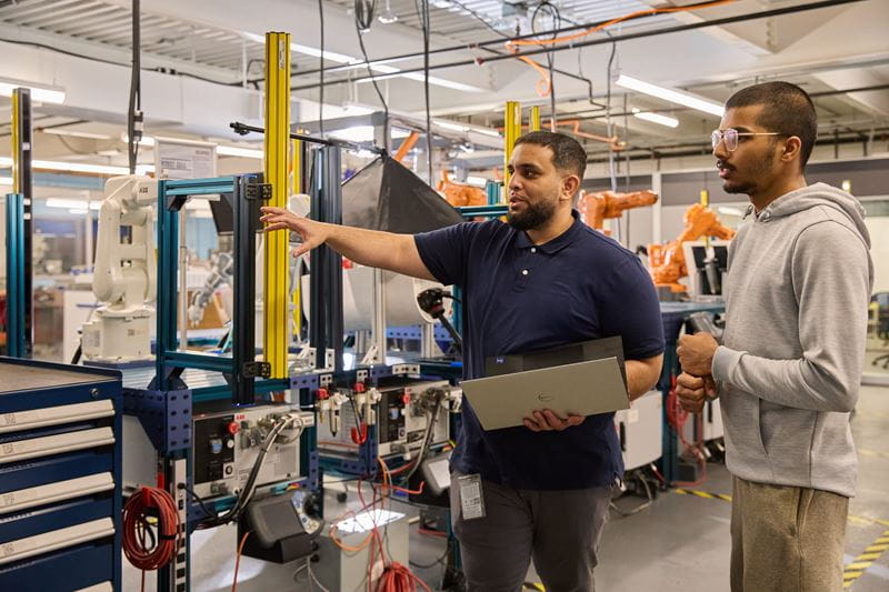 Two men work with equipment in a lab.