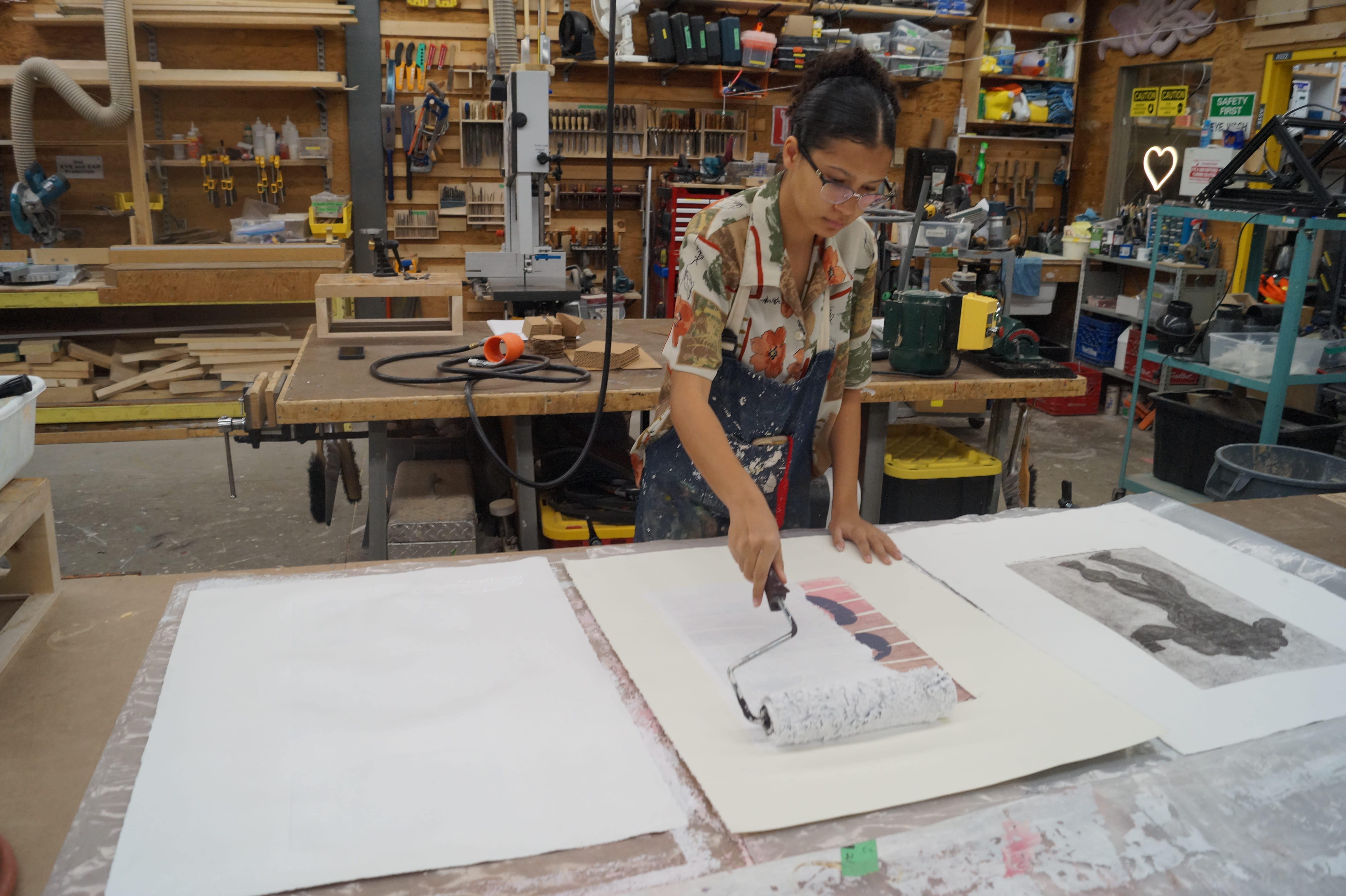 Student Martha Burchert uses a paint roller brush to prime a previously used canvas, turning it white to be used again.