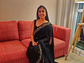 Shweta in formal dress sitting on a red sofa