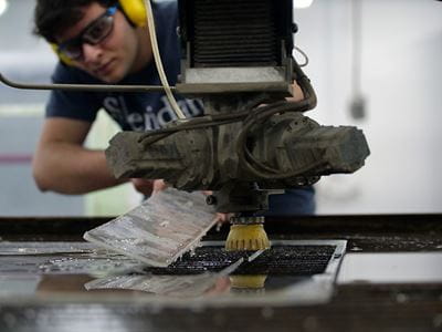 Ramzy Ganady using a water-jet cutter to make a protective shield at Sheridan