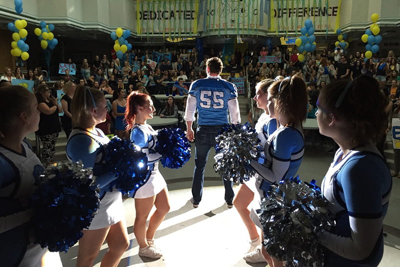 Football player and cheerleaders in a school gymnasium. Still from the film #Roxy