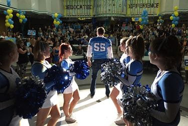 Football player and cheerleaders in a school gymnasium. Still from the film #Roxy