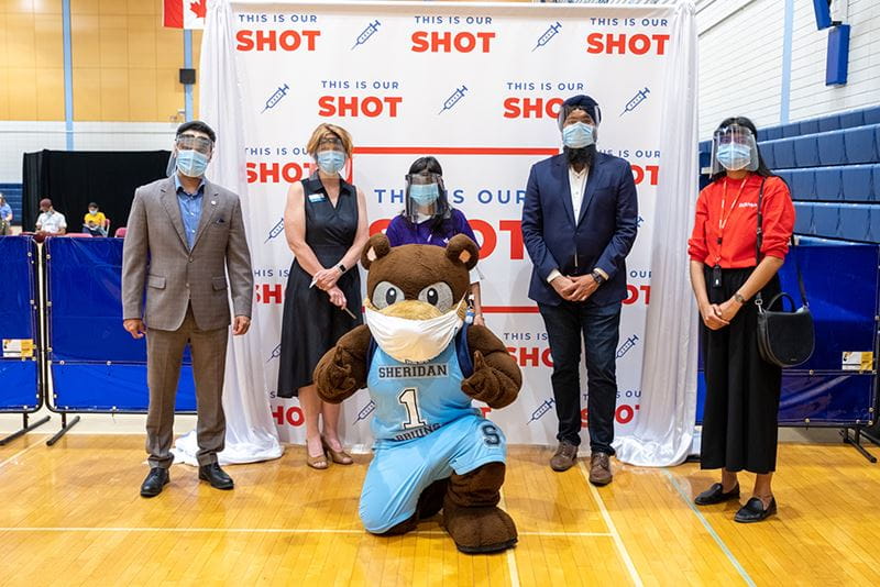 Group of dignitaries in front of 'I got my shot' banner with Sheridan mascot