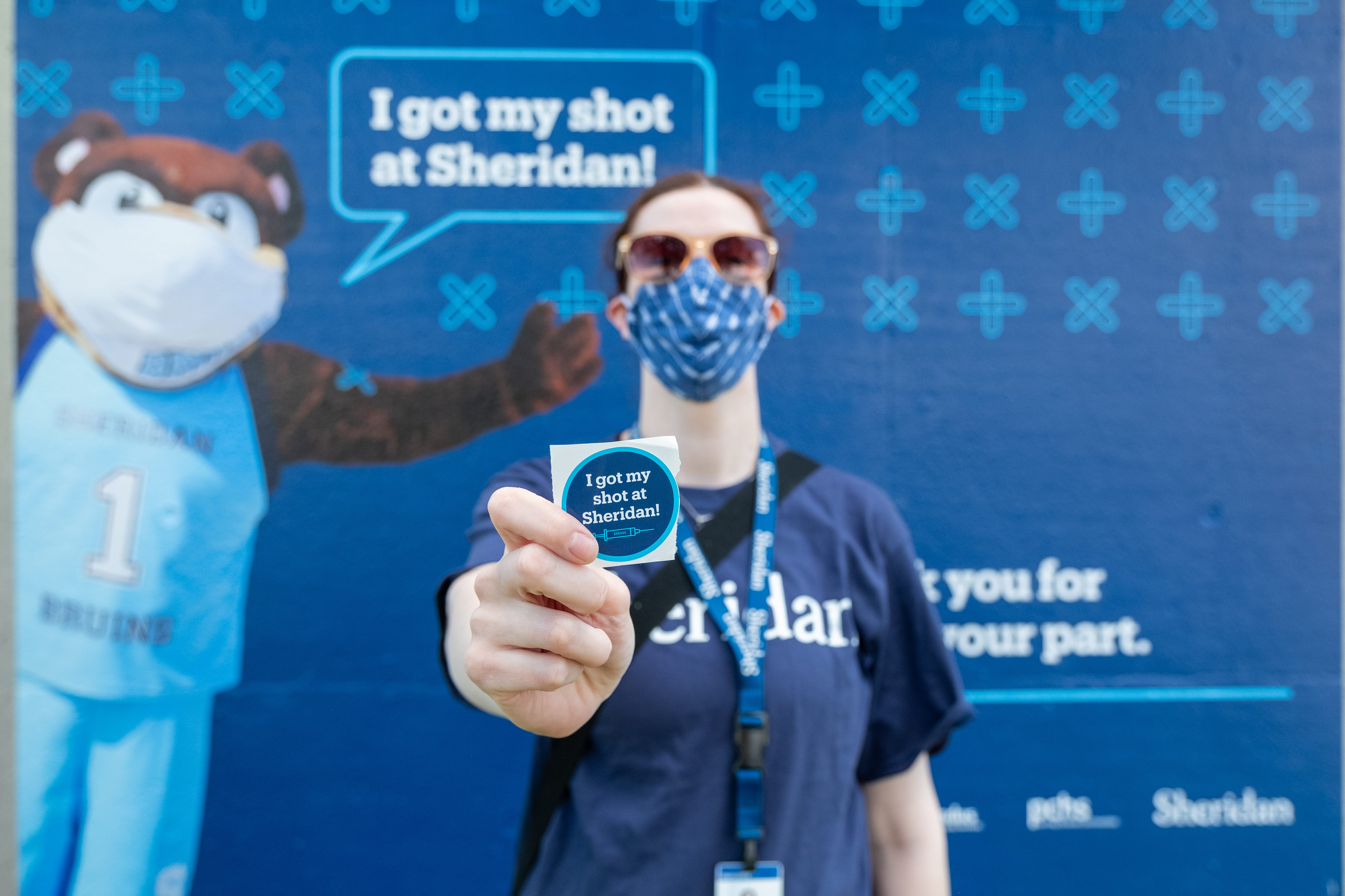 Volunteer holding up 'I got my shot' sticker
