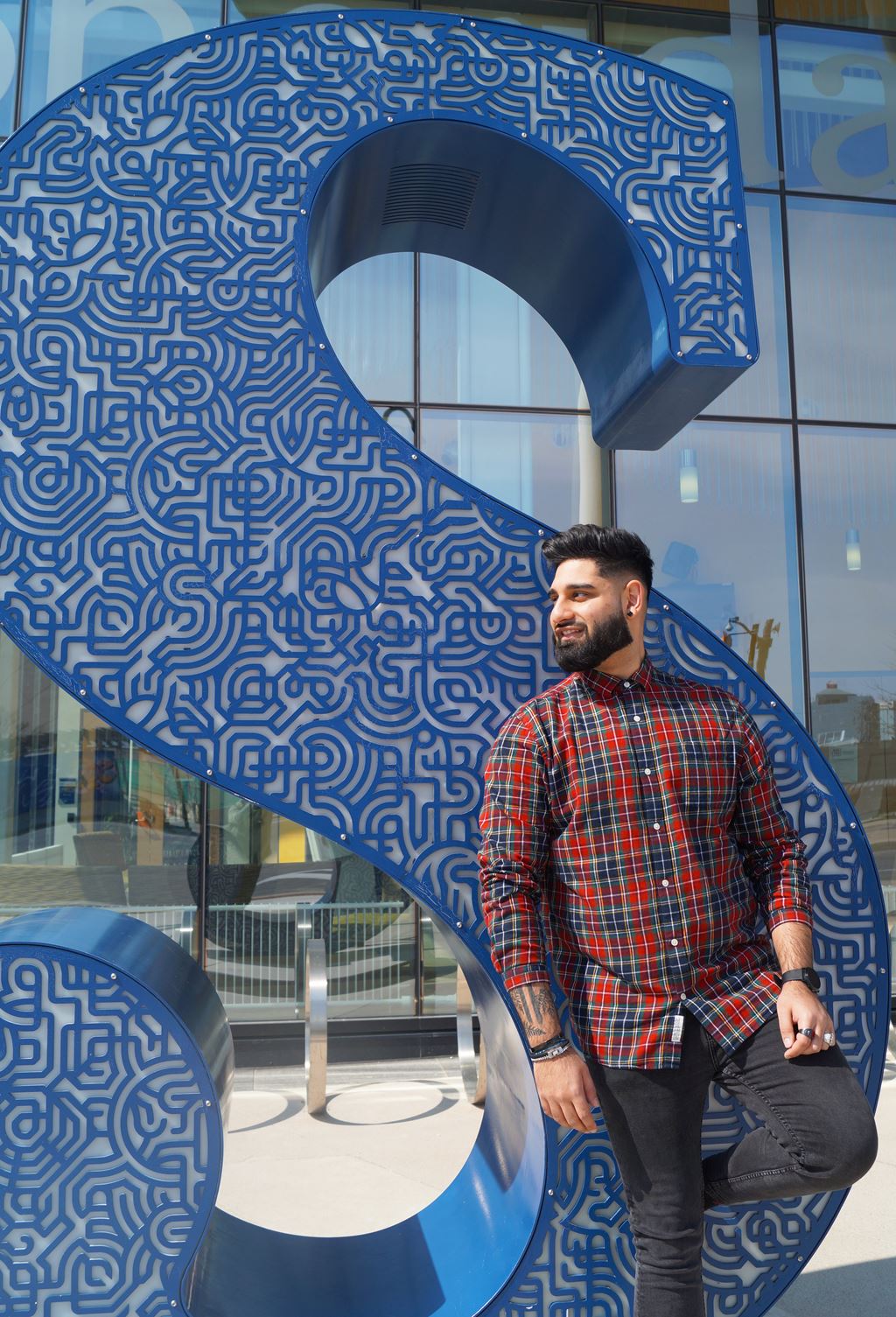 Wali Shah standing in front of the Sheridan S statue outside of the Hazel McCallion Campus