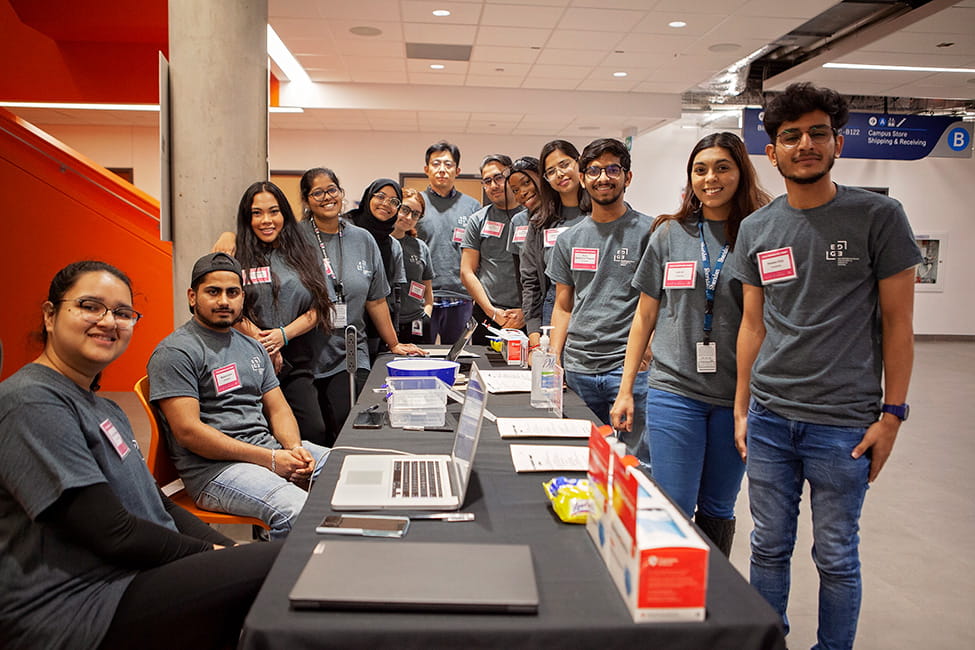 A group dressed in grey EDGE t-shirts gathered around a table