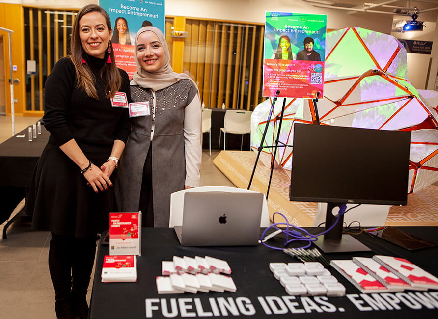 Two people standing behind a display table