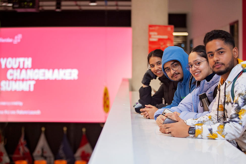 Four people standing next to one another overlooking a presentation area