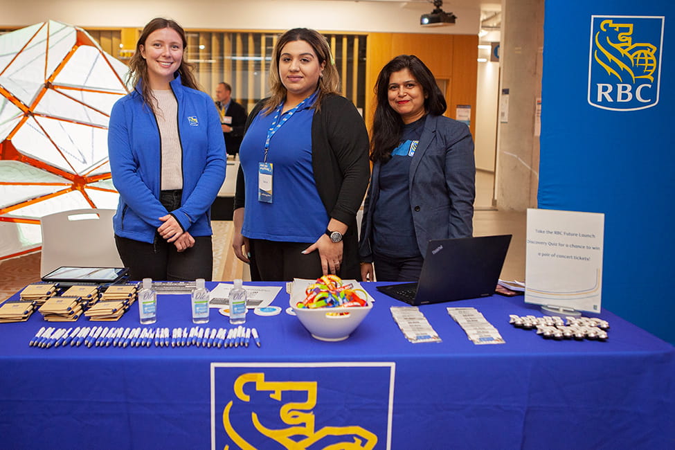 Three people standing behind an RBC display table