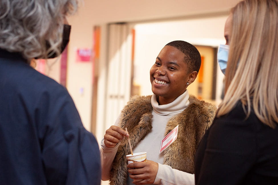 Person smiling and stirring coffee while having a conversation