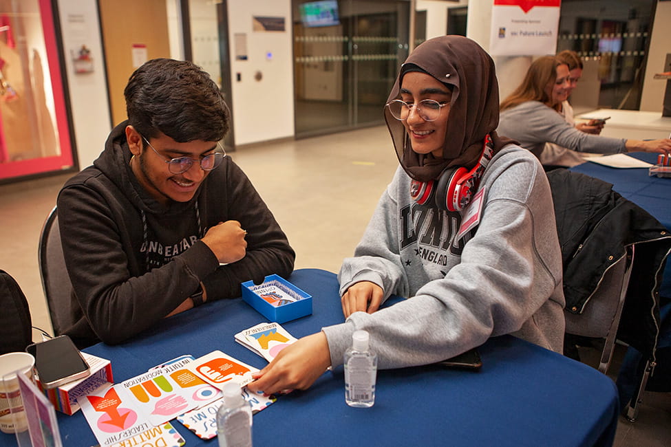 Two students sitting at a table with cards