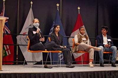 Four past participants in the Social Impact Catalyst program are seated on a stage speaking about their journeys as young entrepreneurs