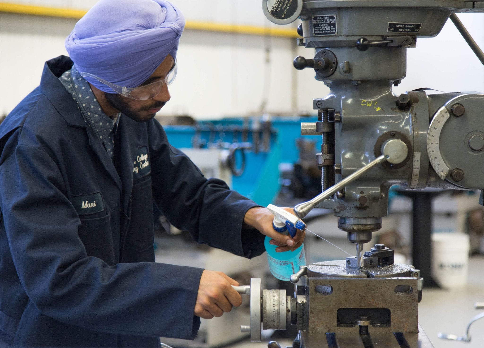 A mechanical technician student sprays a toolmaking machine to clean it.