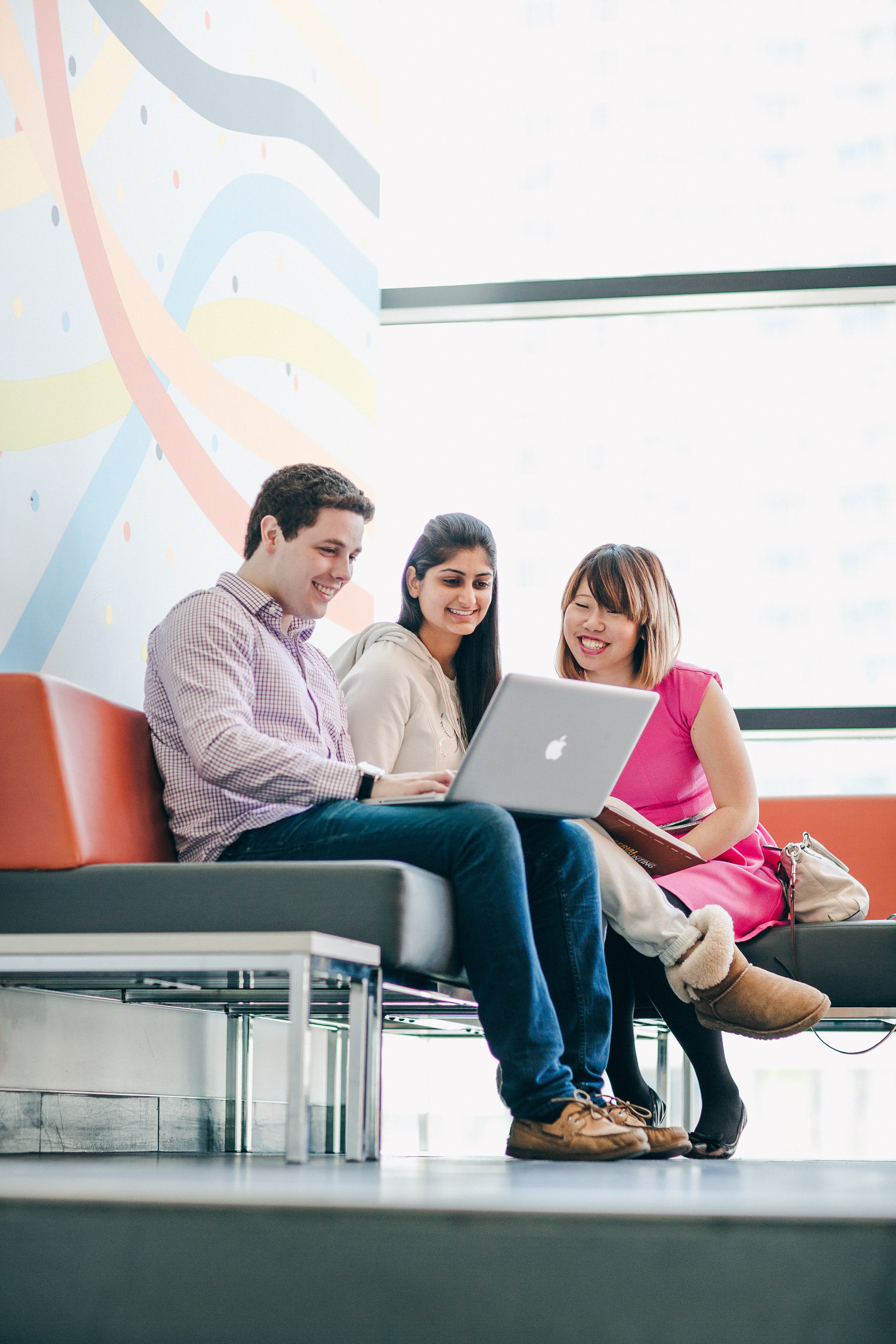 Three students sit together working on a laptop