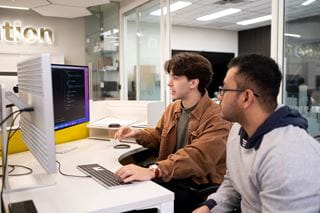 Two students are pictured working together at a computer