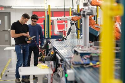Two researchers operate manufacturing robotics in Sheridan's Centre for Intelligent Manufacturing