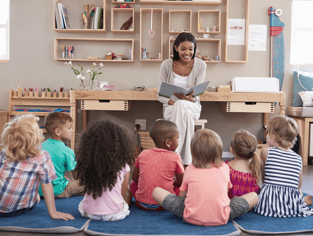 A teacher reads to a group of young children who are sitting on the floor.