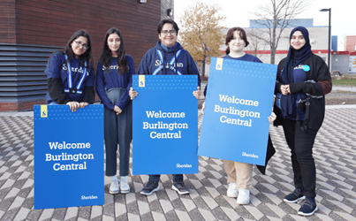Exploration event Sheridan student ambassadors hold signs welcoming high school students