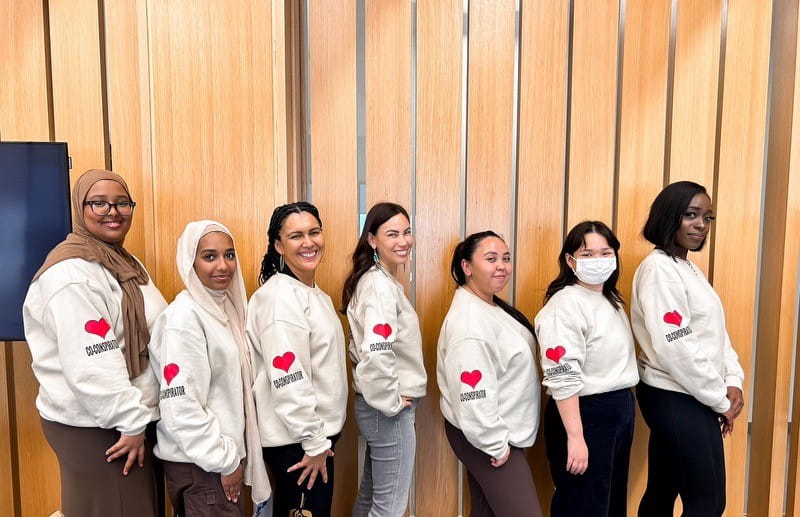 Seven participants in the Hearts and Minds research project stand side by side against a wall