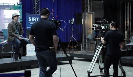 A presenter is filmed on the stage of SIRT during the ICFF Industry Days event.