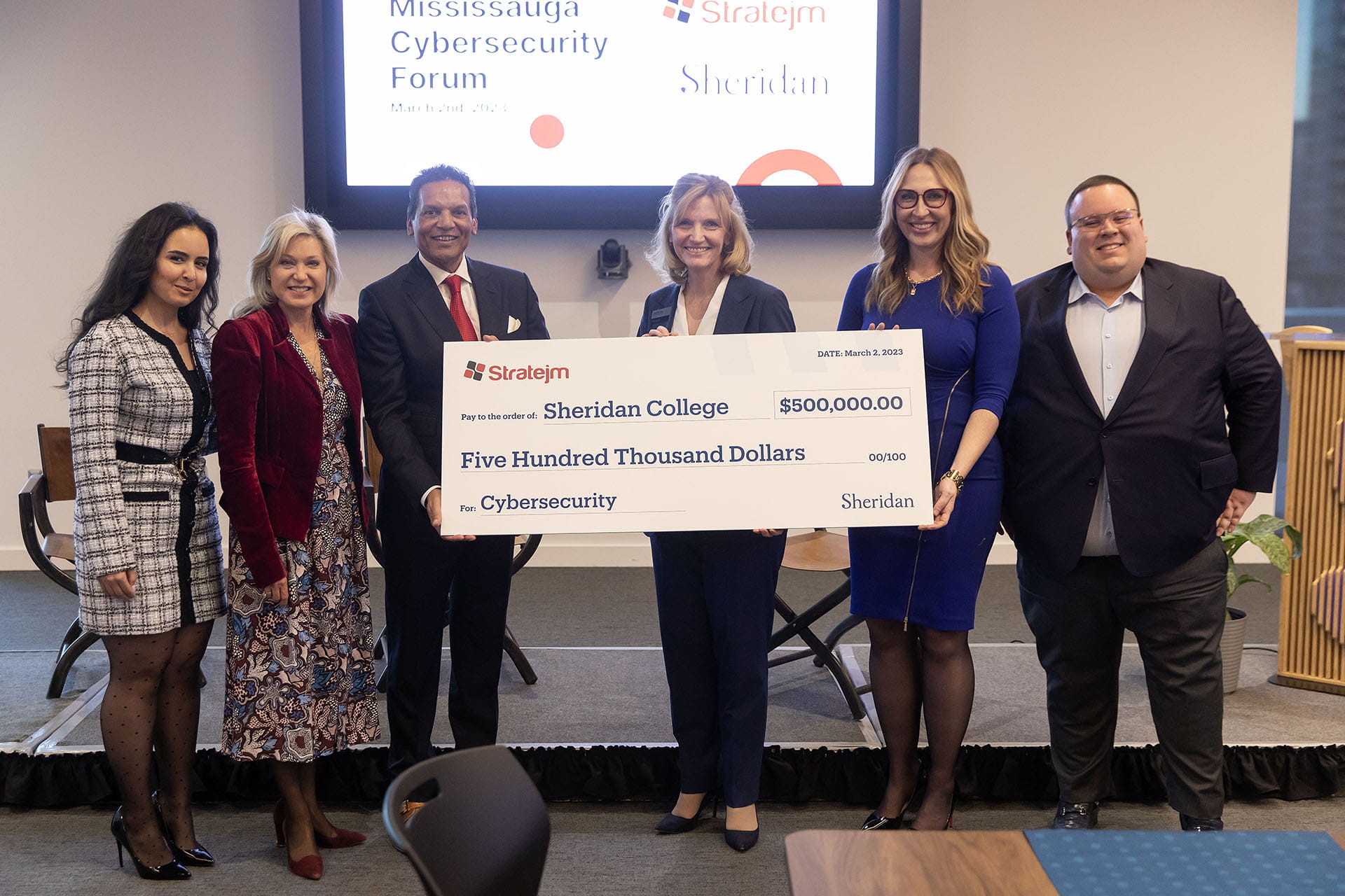 Representatives from Stratejm and Sheridan are pictured holding an oversized cheque for $500,000