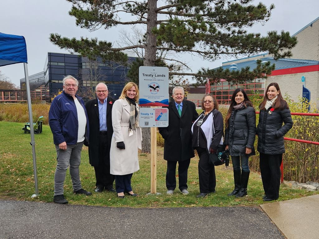 A group stands next to the newly installed treaty sign at Trafalgar campus