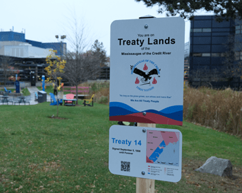 A sign that says Treaty Lands installed on the grass at Trafalgar Campus