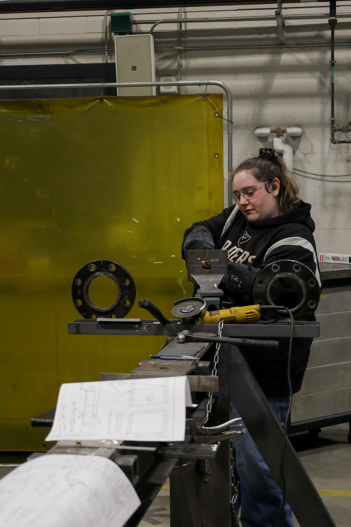 A student operates a metal grinder
