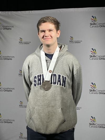 Sheridan student Jacob Christmas stands with a bronze medal around his neck
